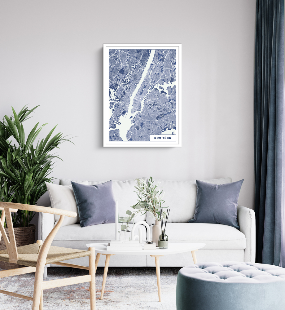 Lámina del mapa de Nueva York en azul y blanco, con marco blanco sobre un sofá claro en un salón con plantas