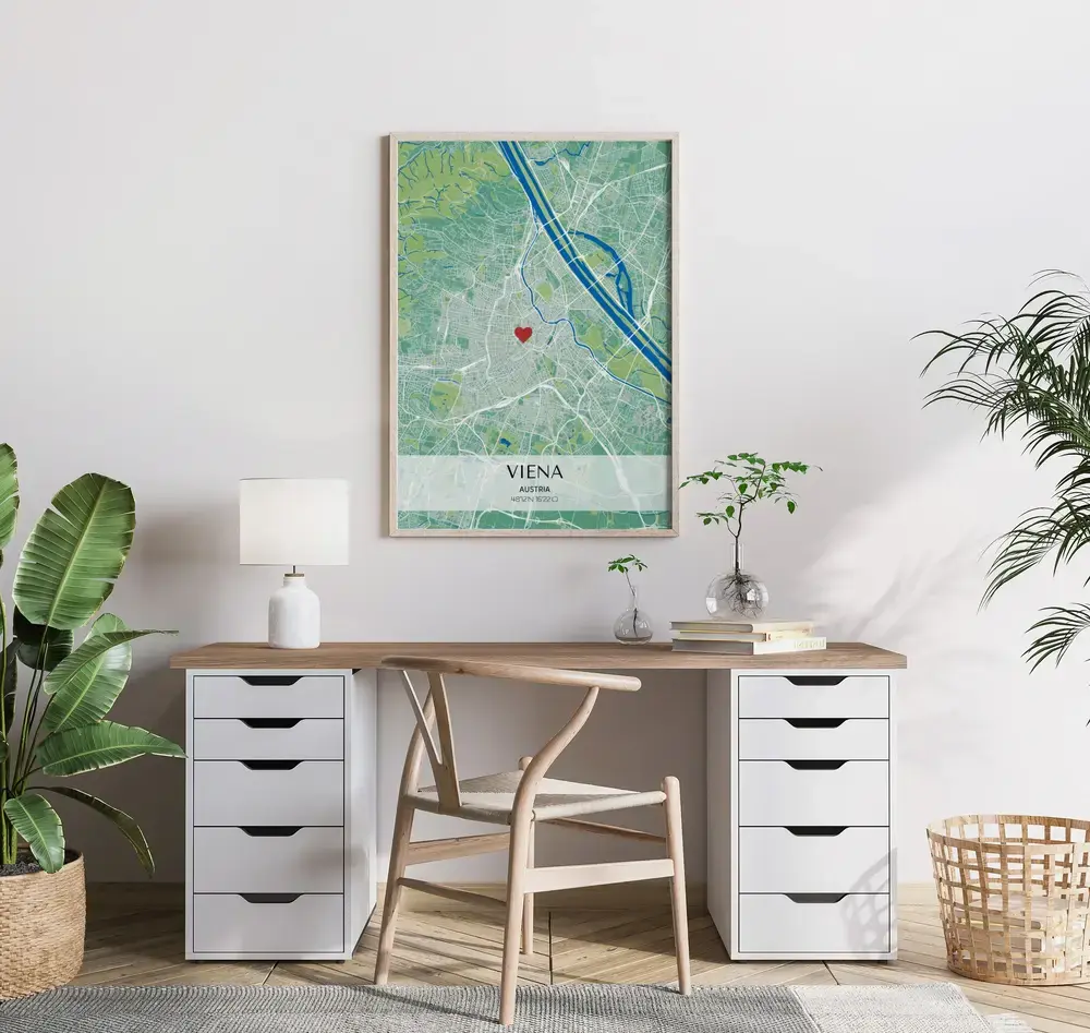 Póster de plano urbano verde y azul con coordenadas y un corazón, enmarcado en madera sobre el escritorio